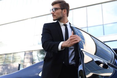 Yakışıklı ciddi genç işadamı onun rahat yeni araba içine oturan ve ofise gidiyor