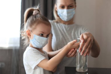 Anne ve küçük kızı alkol dezenfektanı ile ellerini yıkıyor, virüsü ve Covid-19 bakterilerini engelliyor.