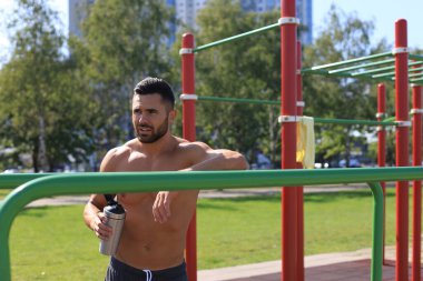 Sporcu su içiyor ve açık havada yoğun bir egzersizden sonra dinleniyor..