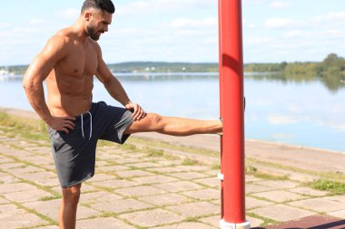 Sportif adam dışarıda bacaklara egzersiz yaptırıyor..