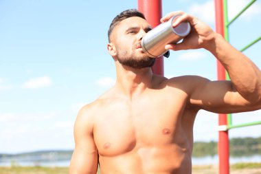 Sporcu su içiyor ve açık havada yoğun bir egzersizden sonra dinleniyor..
