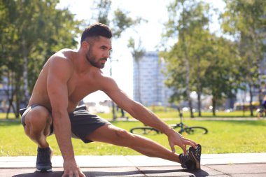 Sportif adam dışarıda bacaklara egzersiz yaptırıyor..