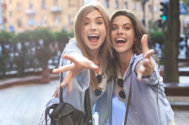 Sokakta poz veren iki genç gülümseyen hippi kadın. Olumlu yüz ifadeleri sergiliyor.