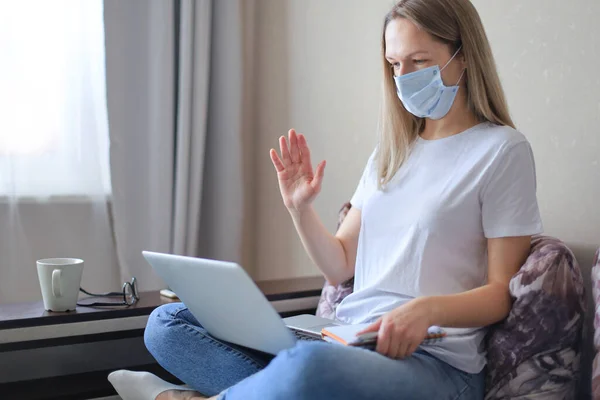 Young woman in medical mask works from home during self isolation and quarantine. Work online and stay at home. Coronavirus outbreak, flu epidemic and covid-19