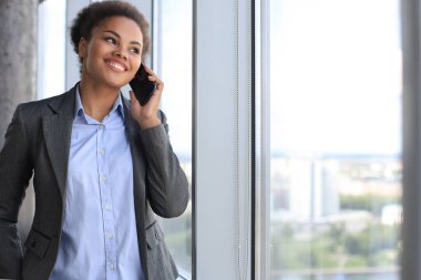 Çekici Afrikalı Amerikalı Amerikalı iş kadını iş arkadaşlarıyla cep telefonundan konuşuyor.