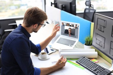 Genç tasarımcı bilgisayardaki meslektaşlarıyla video konferansı yapıyor. Mesafe çalışması. Coronavirüs.