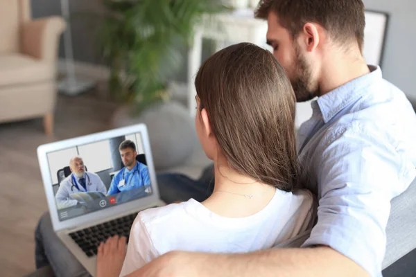 Giovane coppia che fa videoconferenza con i medici sul portatile. Coronavirus . — Foto Stock