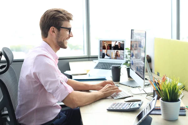 Joven hombre de negocios que trabaja en la computadora, haciendo videoconferencia con colegios en el portátil. Trabajo a distancia. Coronavirus . — Foto de Stock