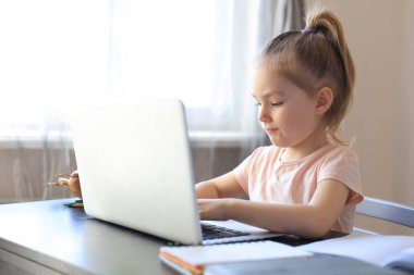 Mesafe öğrenme. Çevrimiçi e-öğrenme sisteminde çalışırken dizüstü bilgisayar kullanan neşeli küçük kız