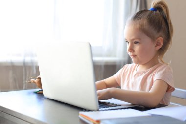 Mesafe öğrenme. Çevrimiçi e-öğrenme sisteminde çalışırken dizüstü bilgisayar kullanan neşeli küçük kız