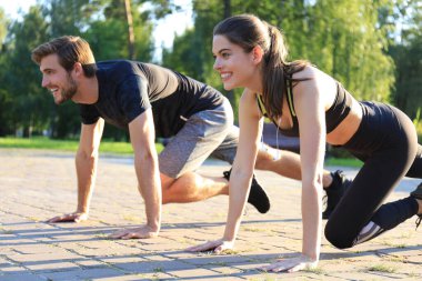 Genç çift parkta spor yaparken birlikte egzersiz yapıyor.