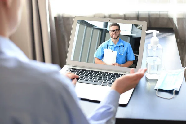 Mujer joven haciendo videoconferencia con el médico en el ordenador portátil. Coronavirus. El uniforme del desgaste del doctor da consulta al Internet del cliente sobre la epidemia, la comunicación distante . — Foto de Stock