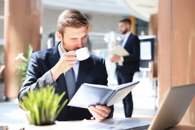 Ofisteki masasında oturan genç adamın portresi.