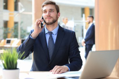İş adamı ofisteki cep telefonunu kullanıyor.