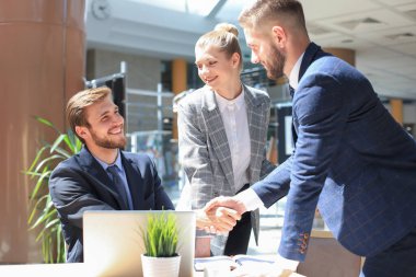 İşadamı, iş arkadaşı ve iş arkadaşlarıyla iş yerinde anlaşma yapmak için el sıkışırken