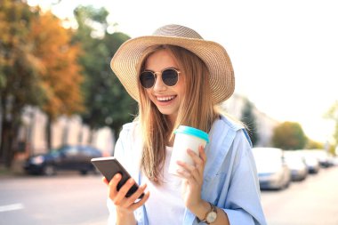 Güzel sarışın kız dışarıda beklerken cep telefonu kullanıyor.