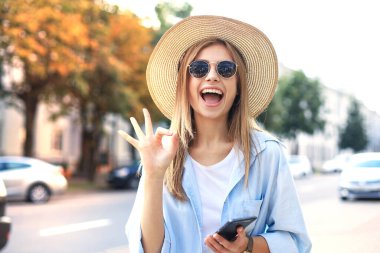 Güzel sarışın kız dışarıda beklerken cep telefonu kullanıyor.