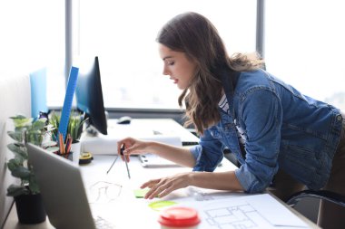 Taslak üzerinde pusula olan genç mimar çizimi ve yaratıcı ofiste çalışırken gülümsemesi.