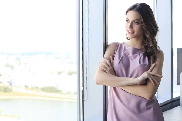 Attractive business woman smiling while standing in the office near the window