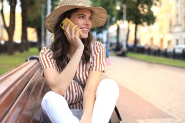 Dışarıda bankta otururken cep telefonuyla konuşan çekici bir kadın..