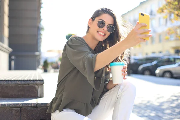 Uśmiechnięta Piękna Brunetka Spaceruje Ulicą Robi Selfie Przez Telefon Komórkowy — Zdjęcie stockowe