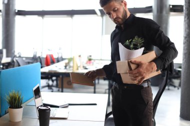 Üzgün işçi ofis malzemelerini yanında götürüyor..