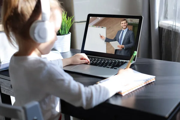 Enseñanza a distancia. Niña alegre en auriculares usando portátil estudiando a través del sistema de e-learning en línea. — Foto de Stock