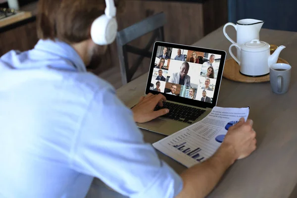 Geschäftsmann mit Kopfhörer spricht während der Selbstisolierung und Quarantäne per Videoanruf mit Kollegen über Online-Briefings. Webcam-Gruppenkonferenz mit Mitarbeitern am Laptop im Büro. — Stockfoto