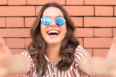 İyimser gülümseyen kız eski duvar arkasında poz veriyor.