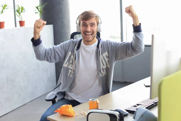 ヘッドフォンでの恍惚としたゲーマーの男の肖像コンピュータ上でビデオゲームをプレイしながら叫びと喜び — ストック写真