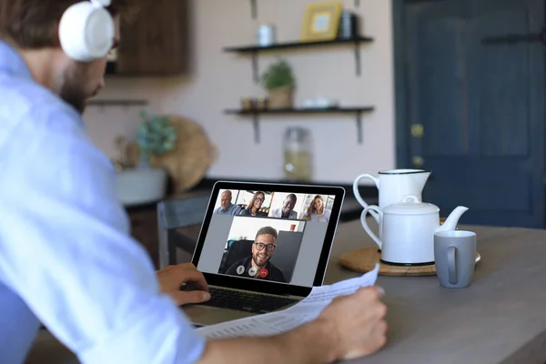 Geschäftsmann mit Kopfhörer spricht während der Selbstisolierung und Quarantäne per Videoanruf mit Kollegen über Online-Briefings. Webcam-Gruppenkonferenz mit Mitarbeitern am Laptop zu Hause. — Stockfoto