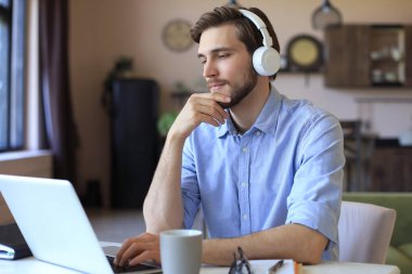 Kulaklık takan kendine güvenen bir adam konuşuyor ve iş kıyafetleri eğitimi izliyor, konferans dinliyor.