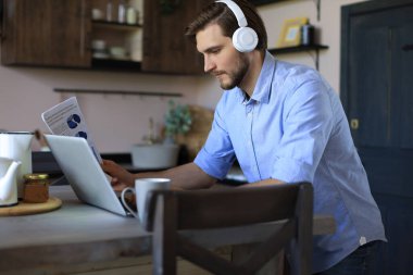 Kulaklık takan kendine güvenen bir adam konuşuyor ve iş kıyafetleri eğitimi izliyor, konferans dinliyor.