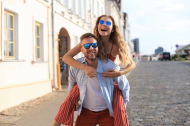 Yakışıklı genç bir adam dışarıda birlikte vakit geçirirken genç ve çekici bir kadını omuzlarında taşıyor..