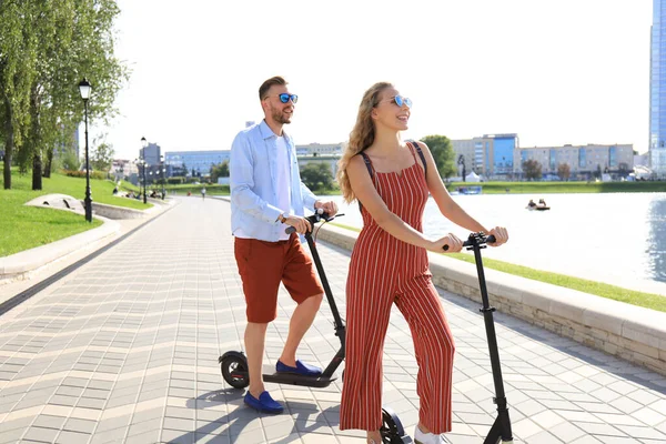 街の遊歩道に沿って楽しい電動スクーターを運転している素敵なカップル — ストック写真