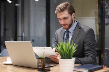 Ofisteki masasında oturan genç adamın portresi.