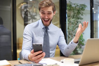 İş adamı ofisteki cep telefonunu kullanıyor.