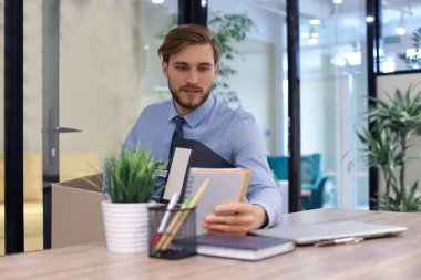 Üzgün işçi ofis malzemelerini yanında götürüyor.