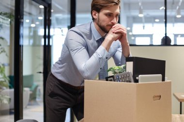 Üzgün işçi ofis malzemelerini yanında götürüyor.
