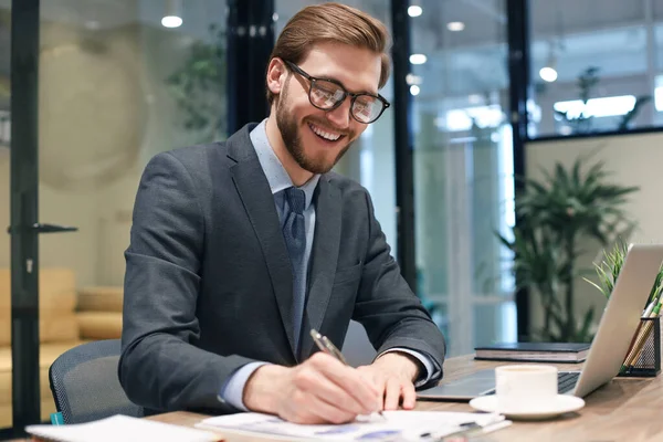 Sonriente Joven Hombre Negocios Escribiendo Algo Mientras Trabaja Oficina Moderna — Foto de Stock