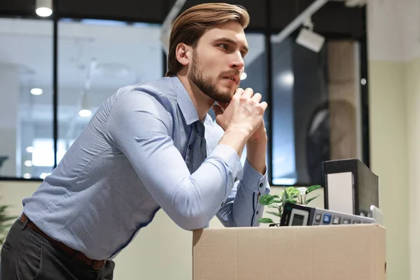 Sad dismissed worker are taking his office supplies with him from office