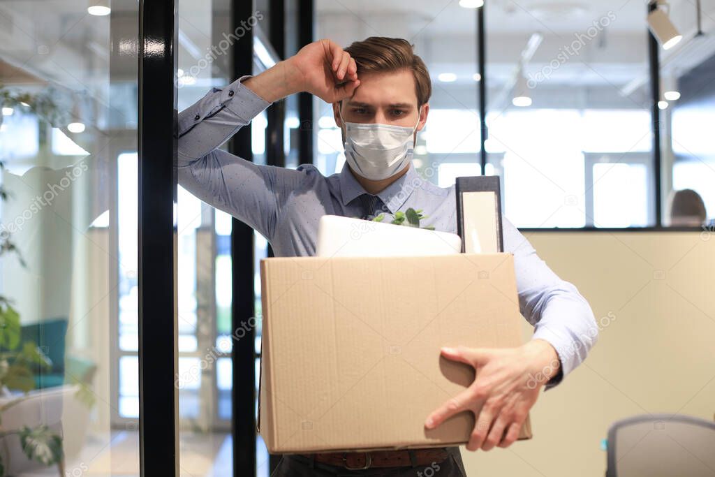 Dismissal employee in preventive medical mask in an epidemic coronavirus. Dismissed worker going from the office with his office supplies