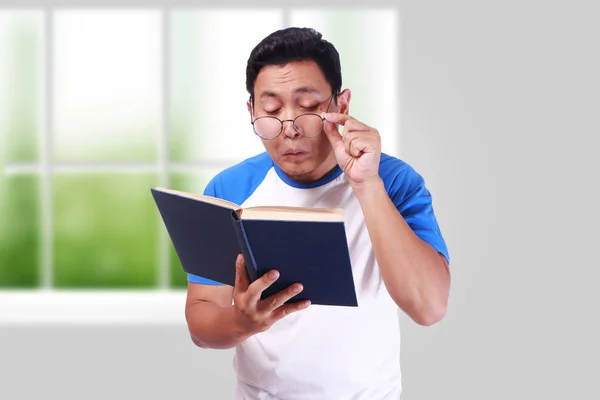 Mladý muž s brýle mají špatné vidění při čtení knihy — Stock fotografie