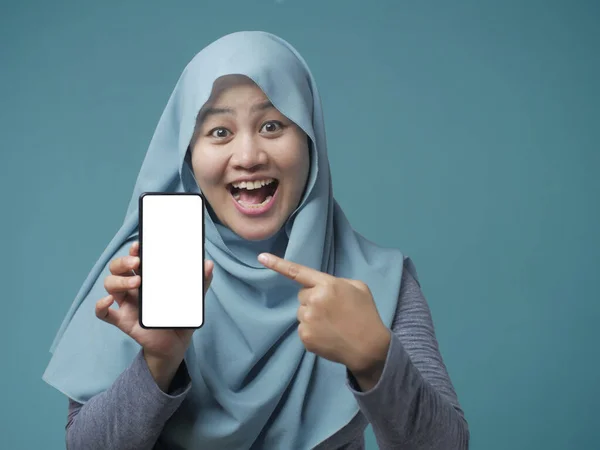 Muslimin blickt lächelnd in Kamera und zeigt Smartphone — Stockfoto