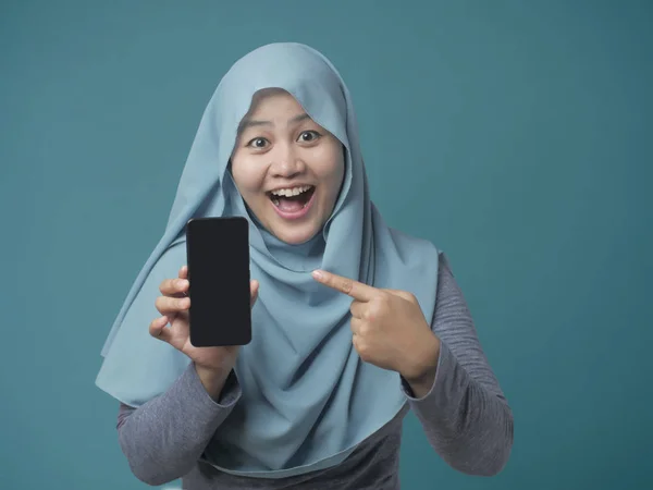 イスラム教徒の女性カメラの笑顔を見て、スマートフォンを表示します。 — ストック写真