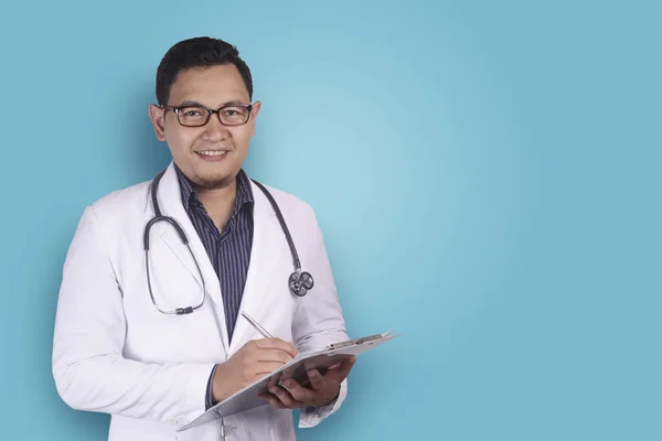 Asian Male Doctor Writing on Clipboard — Stock Photo, Image