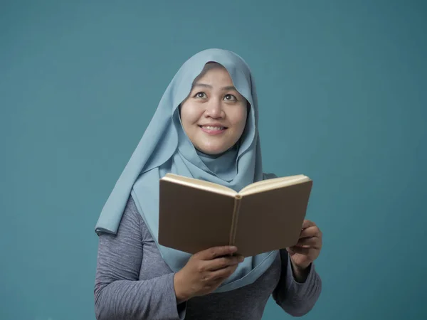 Muslimische Frau hält Buch, denkt nach und lächelt — Stockfoto
