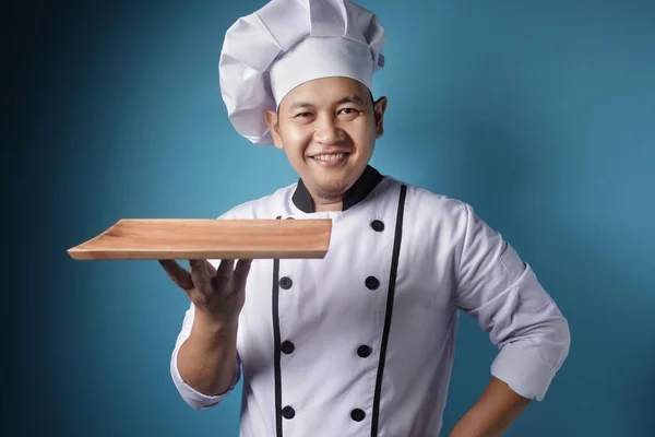 Aziatisch man chef-kok toont lege houten plaat, presenteren iets, — Stockfoto