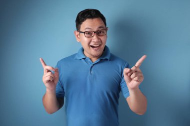 Genç adam iki parmağını havaya kaldırıyor, düşünüyor ve yukarı bakıyor, Havi