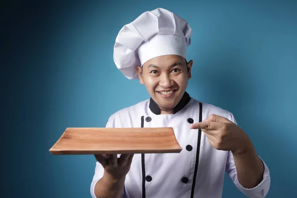 Asian Male Chef Shows Empty Wooden Plate, Presenting Something, — Stock Photo, Image